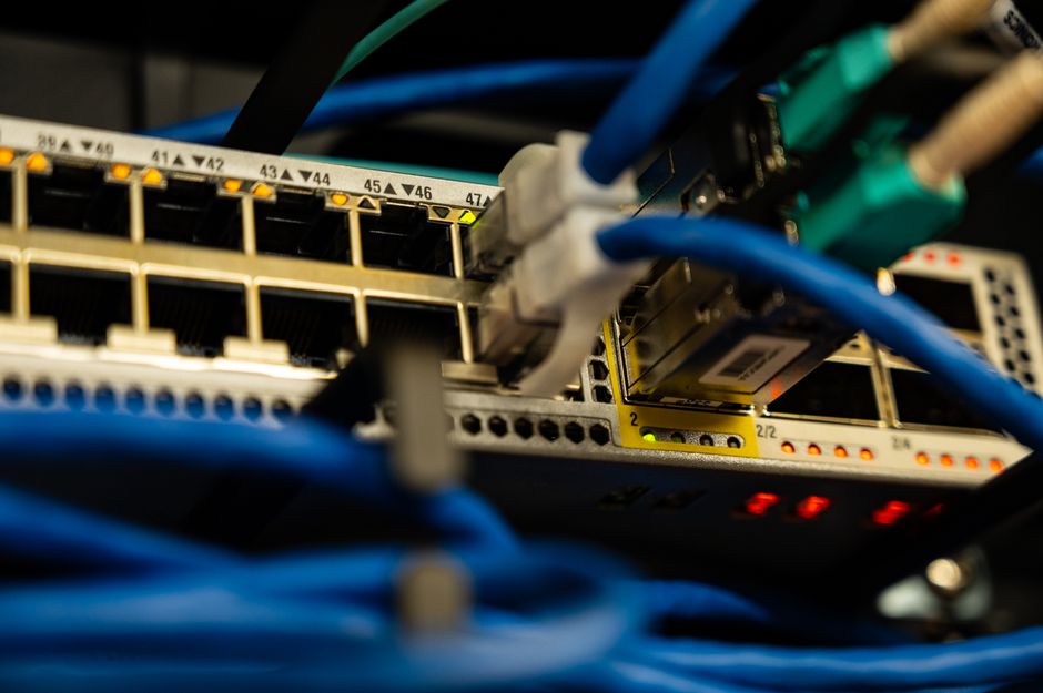 ネットワークスイッチのポートに差さった青いLANケーブルの寄り